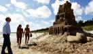 Die Urlauberinnen Kirsten (Mitte) und Grit (rechts) aus Mannheim in Baden-Württemberg spazieren an einer Sandburg am Strand bei Juliusruh auf Rügen entlang, während Organisator Thomas van den Dungen (links) die Skulptur kontrolliert. Tausende Menschen werden für Pfingstsonntag zu einem Weltrekordversuch im Sandburgen-Bauen auf der Insel Rügen erwartet. Einheimische und Touristen sollen mithelfen, eine Burg auf 27,5 Kilometern Länge zu errichten, sagte van den Dungen. Gelingt der Versuch, werde ein seit 20 Jahren gültiger Rekord aus den USA eingestellt. Er liegt bei rund 26,4 Kilometern. Foto: dapd