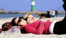 Für ein Sonnenbad reicht die Zeit immer: Am Strand von Warnemünde liegen junge Frauen bei knapp 20 Grad in der Sonne. Foto: ap