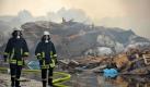 Feuerwehrmänner mit Atemschutzmasken gehen an den Trümmern des durch ein Feuer mit starker Rauchentwicklung zerstörten Geländes des C-Ports in Sedelsberg im Landkreis Cloppenburg entlang. Der Brand ist in einer Lagerhalle ausgebrochen und hat sich auf das Außengelände ausgebreitet. Vor allem Kunststoffabfälle wurden durch die Flammen erfasst.  Foto: dpa