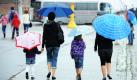 Touristen gehen mit Regenschirmen durch den Hafen in Stralsund. Auch für die nächsten Tage haben die Meteorologen vorerst kühles und regnerisches Wetter vorausgesagt.  Foto: dpa