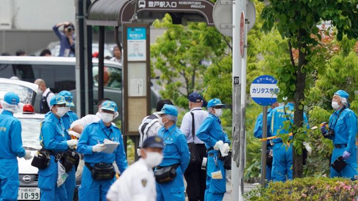 Ermittler sind neben einer Bushaltestelle für den Bus der CARITAS Grundschule am Tatort in Kawasaki im Einsatz.