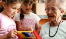 Chantal (links) und Johanna aus einer Kitagruppe versuchen sich mit der 80-jährigen Ruth Matthies in einem Pflegeheim in Brandenburg (Havel) an einem Rechenbrett. In dem bundesweit einzigartigen Modellprojekt Glücksmomente der Arbeiterwohlfahrt (AWO) leben ältere Menschen mit einer Kindergartengruppe unter einem Dach zusammen. Foto: dpa