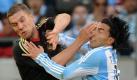 Handgreiflichkeiten inklusive: Hier beharken sich Lukas Podolski und der Argentinier Carlos Tevez. An diesen eingefrorenen Sekundenbruchteilen sieht man, wie bei aller Rafinesse nicht gerade mit Wattebäuschchen geworfen wird. Foto: dpa