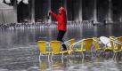 So kann man dem Regen auch trotzen: Mit einer Flasche in der Hand tanzt eine Frau auf dem Markusplatz in Venedig. Am Morgen stieg der Wasserstand in der italienischen Lagunenstadt auf 102 Zentimeter über dem Normalpegel. Foto: dpa