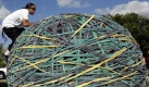 Joel Waul, 28, climbs on top of his rubber band ball on the driveway of his home in Lauderhill, Fla., Friday, Oct. 23, 2009. Waul who works nights restocking a Gap clothing store, has spent the last six years carefully wrapping and linking and stretching rubber bands of various sizes into the ball shape. The Guinness Book of World Records declared it the world's largest rubber band ball in 2008. (AP Photo/Alan Diaz) Foto: ap