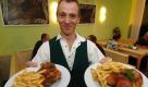 Der Kellner Peter Müller zeigt am Montag (12.09.2005) in der Goldbroiler-Bar in Erfurt die traditionellen halben Brathähnchen (Broiler) nach DDR-Rezept. Der 53-jährige Gastronom Dieter Heck eröffnet an diesem Tag die in Ostdeutschland beliebte Broiler-Gaststätte mit Geschirr und auch einigen Sitzplätzen nach orginalem Vorbild. Bereits von 1970 bis 1991 hatte es in Erfurt eine Goldbroiler-Bar gegeben. Foto: Martin Schutt dpa/lth +++(c) dpa - Bildfunk+++
 Foto: dpa