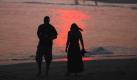 Zwei Spaziergänger laufen während des Sonnenuntergangs am Strand von Cape May im US-Bundesstaat New Jersey entlang. Auch die amerikanische Ostküste schwitzt derzeit  bei hochsommerlichen Temperaturen.  Foto: ap