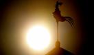 Kurzzeitig zeigt sich die Sonne am Himmel hinter einem Wetterhahn im brandenburgischen Jacobsdorf. Foto: dpa