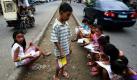 Philippinische Kinder sitzen auf einer Straße in einem Armenviertel in Manila und schreiben Hausaufgaben in ihre Übungshefte. Knapp 23 Millionen Schüler werden in diesem Schuljahr an philippinischen Schulen unterrichtet. Das Bildungsministerium des Landes fordert deswegen mehr Geld für Bildungsfonds. Foto: dpa