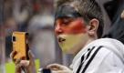 Echte Fans zeigen sich auch als solche. In den Farben Deutschland beobachtet dieser junge Mann die Aufwärmphase des deutschen Eishockeyteams. Foto: ap
