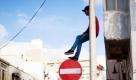 Einen ungewöhnlichen Platz zum Ausruhen hat sich dieser Libyer ausgesucht. Im Zentrum von Bengasi kletterte er einfach auf eine Straßenlampe und nutzte das Straßenschild als Fußbank. Foto: dapd