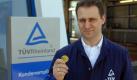 Ein Archivbild zeigt einen Mitarbeiter des TÜV Rheinland mit einer Prüfplakette. Foto: ddp