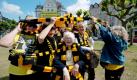 Mit den Resten des vermutlich längsten BVB-Fanschals wickelt sich eine Frauengruppe um die 82-jährige Ilse Schilling (Mitte) auf dem Borsigplatz in Dortmund ein. Über 100 Menschen im Alter von 6-86 Jahren strickten jeweils einen einzelnen Schal, aus dem nun ein einziger zusammengesetzt wurde, der einmal um den ganzen Borsigplatz gewickelt wurde. Der Gewerbeverein hatte bereits im Februar dazu aufgerufen, für die Meisterschaft zu stricken. Foto: dpa