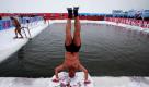 Der 73-jährige Chinese Xiao Ying macht einen Handstand, bevor er in das Eiswasser in Harbin, im Nordosten Chinas, springt. Foto: ap