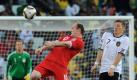 Noch einmal Deutschland - England: Wayne Rooney und Bastian Schweinsteiger üben sich beim Kopfballduell im Grimassenschneiden. Im Hintergrund, direkt unter Rooneys Füßen, sind die aufgereihten Hintertorkameras zu erahnen, die von den Fotografen per Funk ausgelöst werden.

 Foto: dpa