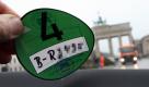 Eine grüne Plakette zeigt ein Fahrzeughalter am Donnerstag (27.12.2007) in Berlin. Im Hintergrund steht das Brandenburger Tor. Ab dem 01.01.2008 dürfen nur noch Fahrzeuge mit grüner, gelber und roter Feinstaubplakette die Umweltzone der Bundeshauptstadt befahren. Dadurch sollen die gesundheitsschädlichen Schadstoffkonzentrationen in der Luft verringert werden.
 Foto: dpa