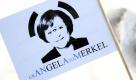 Eine Teilnehmerin eines Ostermarsches hält am Samstag (23.04.11) in Ohrdruf eine Fahne, die Bundeskanzlerin Angela Merkel (CDU) mit drei Augen in einem Symbol fuer Radioaktivität zeigt. Rund 150 Menschen haben am Samstag in Ohrdruf für ein Ende der Auslandseinsätze der Bundeswehr und einen baldigen Atomausstieg demonstriert. Foto: dapd