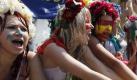 Members of the Ukrainian feminist group FEMEN, decorated as soccer fans, shout slogans while standing in a public fountain during their action in the Independence square in Kiev, Ukraine, 14 July 2011. The FEMEN activists had taken off most of their cloth Foto: dpa