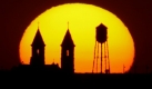 The twin spires of St. Fidelis Church and a municipal water tower are distorted by heat vapors as they are silhouetted by the setting sun Monday, Oct, 19, 2009 in Victoria, Kan. The Catholic church inspired William Jennings Bryan to call it the 'Cathedral of the Plains' during a visit in 1912. (AP Photo/Charlie Riedel) Foto: ap