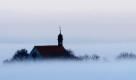 Die Vogelsburg ragt bei Volkach (Unterfranken) aus dichtem Nebel hervor. Laut Vorhersage der Meteorologen bleibt das Wetter in Bayern in den kommenden Tagen meist regnerisch und für die Jahreszeit verhältnismäßig mild.
 Foto: dpa