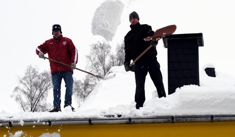 Mitarbeiter einer Schreinerei räumen in Wenden-Rothemühle Schnee vom Dach einer Werkhalle. Das Winterwetter hat im Sauerland auch zu erheblichen Verkehrsbehinderungen geführt. 
 Foto: dpa