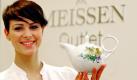 Vor dem Logo der Staatlichen Porzellan-Manufaktur Meissen nahe Dresden präsentiert Porzellanmalerin Maria Neumärker am Dienstag (10.03.2009) eine Teekanne aus einer Frühlingskollektion. Anlass ist die Eröffnung des sogenannten 'Meissen-Outlet' Geschäftes in der Porzellanmanufaktur. Hier soll das wertvolle Tafelporzellan in Zweitsortierung vergünstigt angeboten werden und mehr Touristen nach Meissen locken. Im Stammhaus Meissen konnte der Umsatz mit dem Luxusporzellan im Februar um 23 Prozent im Vergleich zum Vorjahr gesteigert werden. Die 1710 gegründete Manufaktur Meissen beschäftigt heute 800 Mitarbeiter. Foto: Ralf Hirschberger dpa/lsn +++(c) dpa - Bildfunk+++ Foto: dpa
