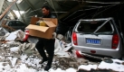 Ein Mann trägt seine Sachen aus seinem beschädigten Auto. Das Dach des Gebäudes ist durch die Schneelast zusammengebrochen. Im Norden Chinas haben heftige Schneestürme mehrere Todesopfer gefordert. Foto: ap