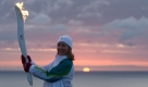 Die Fackelträgerin  Donna O'Grady hält das Olympische Feuer, während im Hintergrund die Sonne in Cape Spear, Kanada, aufgeht. Cape Spear ist der östlichste Punkt Nordamerikas. Die Fackel wird 1000 Städte besuchen, bis sie im Februar die Olympischen Winterspiele eröffnet. Foto: ap