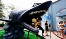 Erstaunlich unerschrocken für einen Knirps, der beinahe von einem Hai verschlungen wird: Eine Frau rettet ein Kind aus dem Maul einer Haiskulptur vor einem Aquarium im chinesischen Beijing. Foto: ap