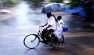 Teamwork: Ein indischer Radfahrer nimmt einen anderen Mann mit, der ihm den Regenschirm hält. Der Zyklon Leila bringt in Teilen Indiens starke Regenfälle. Foto: dpa