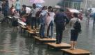 Mit einer Brücke aus Tischen helfen sich die Bewohner im überfluteten, zentralchinesischen Wuhan. Foto: Yuan Zheng Foto: dpa