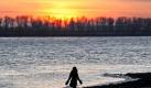 Warm eingepackt geht eine Passantin bei Sonnenuntergang an der Elbe in Hamburg spazieren. Das sibirische Hochdruckgebiet 'Cooper' bringt eisige Luft nach Deutschland. Foto: Bodo Marks Foto: dpa