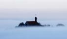 Die Vogelsburg ragt bei Volkach (Unterfranken) aus dichtem Nebel hervor. Laut Vorhersage der Meteorologen bleibt das Wetter in Bayern in den kommenden Tagen meist regnerisch und für die Jahreszeit verhältnismäßig mild.
 Foto: dpa