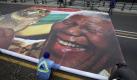 Workers prepares to install an image of Nelson Mandela holding the FIFA trophy on the Nelson Mandela Bridge leading in to downtown Johannesburg, Sunday, May 30, 2010. The bridge is being festooned with an array of banners, flashing new lights, African flags and banners ahead of the FIFA World Cup Soccer Tournament which gets underway June 11. (AP Photo/Denis Farrell) Foto: ap