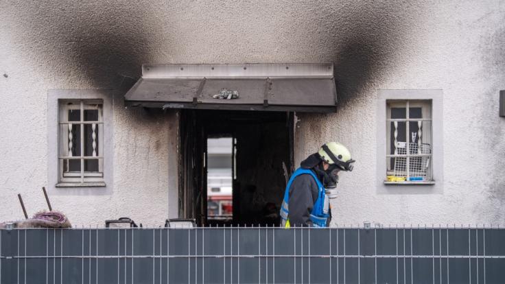 Ein Feuerwehrmann mit Atemschutzausrüstung verlässt nach einem Brand ein Haus. Bei dem Brand in dem Nürnberger Wohnhaus sind vier Kinder und eine Frau ums Leben gekommen.