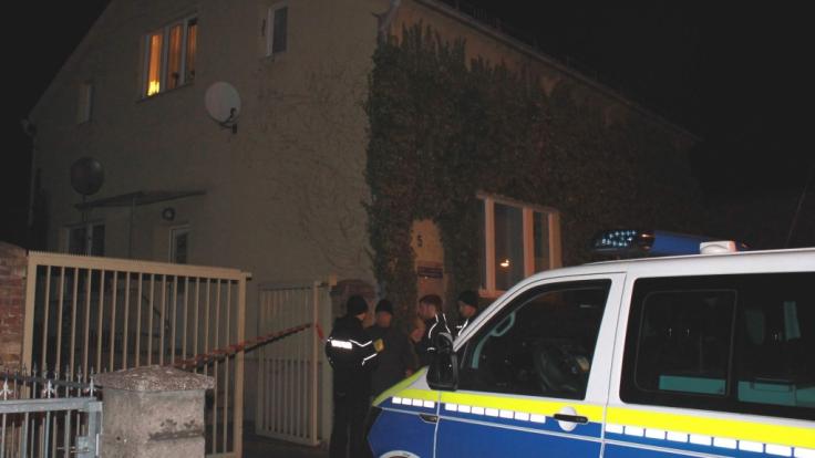 Ein Polizeiauto und Polizisten stehen vor dem Grundstück, auf dem ein Mann erschossen wurde.