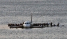 Airline passengers wait to board a ferry to be rescued on the wings of a US Airways Airbus 320 jetliner that safely ditched in the frigid waters of the Hudson River in New York, Thursday Jan. 15, 2009 after a flock of birds knocked out both its engines. All 155 people on board survived. (AP Photo/Steven Day) Foto: ap