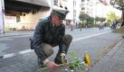 In Polizist legt in Lörrach vor dem Wohnhaus, in dem sich die ausgebrannte Wohnung der Amokläuferin von Lörrach befindet, eine Sonnenblume nieder. Foto: dpa