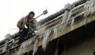 Ein Mann beseitigt Eiszapfen, die von einem Dach in der polnischen Haupstadt Warschau hängen. Foto: ap