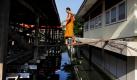 Auf seinem Weg durch einen überfluteten Stadtteil von Bangkok läuft ein buddhistischer Mönch über ein schmales Brett. Mittlerweile hat das Hochwasser den nördlichen Rand der Innenstadt erreicht und bedroht das U-Bahnsystem der Stadt. Foto: dapd