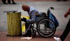 Ein Chinese in einem Rollstuhl durchsucht einen Mülleimer in Peking nach recycelbarem Material. Foto: ap