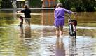 Zwei Frauen schieben in Starnberg am Ufer des Starnberger Sees ihre Fahrräder durch das Wasser einer überfluteten Straße. Andauernder Regen hat in Teilen Südbayerns Feuerwehr und Polizei auf Trab gehalten. Keller liefen voll Wasser, Straßen wurden überflutet.  Foto: dpa