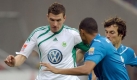 Christian Eichner (r) und Marvin Compper kümmern sich um Wolfsburgs Edin Dzeko. Dem gelingt diesmal kein eigener Treffer. Foto: dpa