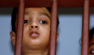 Flüchtlinge aus Sri Lanka sehen aus einem Fenster des Auffanglagers auf der indonesischen Insel Bintan. 
 Foto: ap