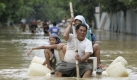 Mit einem improvisierten Boot paddelt ein Mann mit seiner Familie in einem Vorort von Pasig, östlich von Manila. Foto: ap