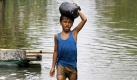 Ein philippinischer Junge trägt seine Habseligkeiten durch das überflutete Gebiet in der Stadt Pasig City, östlich der Haupstadt Manila. Starke Winde und Regen, die durch Taifune entstanden waren, brachten den Fluss zum überlaufen. Foto: dpa
