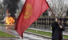 A Kyrgyz protester waves the national flag as a vehicle burns in Bishkek, Kyrgyzstan, Wednesday, April 7, 2010, following clashes with police. Police in Kyrgyzstan opened fire on thousands of angry protesters who tried to seize the main government building amid rioting in the capital as protests spread across the Central Asian nation. (AP Photo/Ivan Sekretarev) Foto: ap