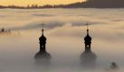 Zwillingstürme im Nebelmeer: Die Türme der Klosterkirche von St.Peter im Schwarzwald ragen im Abendlicht aus dem Nebel. Foto: Rolf Haid Foto: dpa