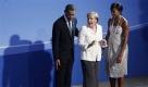 President Barack Obama points to a toe marker for a group photo as he and first lady Michelle Obama welcome German Chancellor Angela Merkel as they arrive for the G-20 summit dinner in Pittsburgh, Thursday, Sept. 24, 2009. (AP Photo/Charles Dharapak) Foto: ap