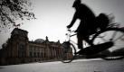 Eine Radfahrerin fährt in Berlin über einen verschneiten Weg vor dem Reichstag. Schnee und überfrierende Nässe haben in verschiedenen Teilen der Hauptstadt zu Verkehrsbehinderungen geführt.
 Foto: ddp
